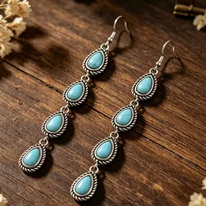 Dettaglio di orecchini boho con turchese a goccia su sfondo in legno rustico
