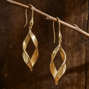 Primer plano de pendientes dorados en forma de hoja con una elegante textura vertical
