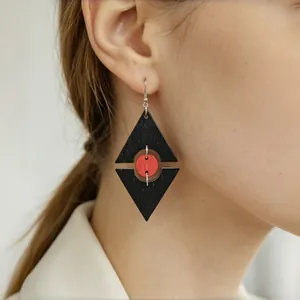 Primo piano di orecchini geometrici in legno rosso e nero a forma di rombo traforato per donna