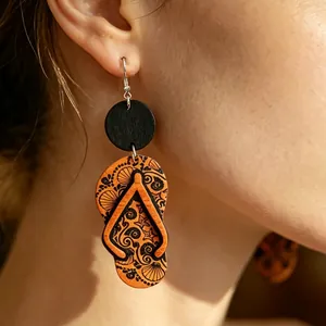Primer plano detallado de pendientes de madera vintage con forma de chanclas y motivos negros