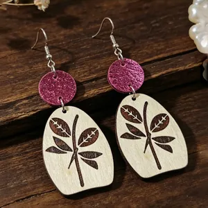 Primer plano de pendientes retro de madera con estampado de hojas y purpurina magenta