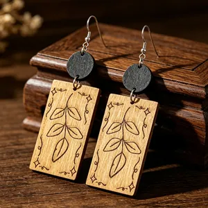 Vista detallada de los pendientes retro de madera con grabados de hojas y estrellas