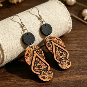 Detalle de pendientes de madera con forma de chancla y motivos de conchas y olas