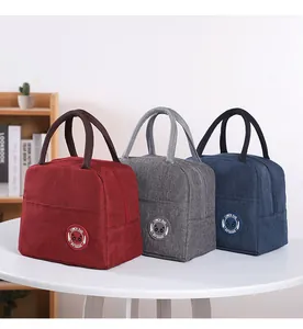 Insulated Oxford cloth lunch bags in red, grey, and navy blue colors on a white table.