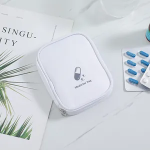 Portable white first aid pouch for travel medicine storage on a marble tabletop