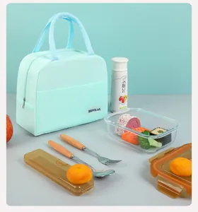 Mint green insulated lunch bag shown with a glass meal prep container and wooden cutlery