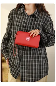 Pochette en nylon rouge de grande capacité avec dragonne tenue par un mannequin en chemise