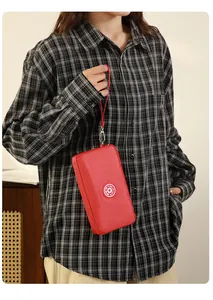 Vue détaillée d'une pochette de téléphone rouge minimaliste avec dragonne tenue par un mannequin