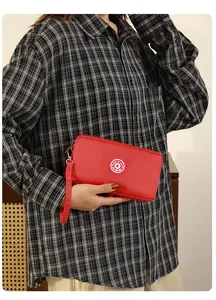 Gros plan d'une pochette en nylon rouge tenue par une personne en chemise à carreaux