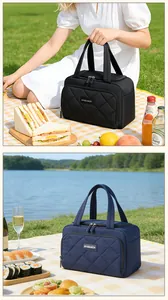 Gewatteerde geïsoleerde lunchtas in zwart en marineblauw getoond in een picknicksetting