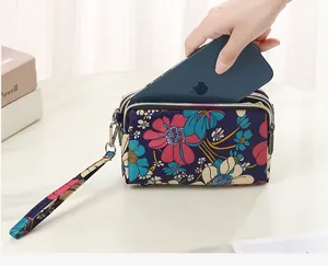 Detailed view of a floral triple-zip pouch storing a smartphone on a white desk