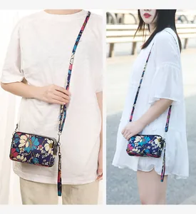 Detailed view of floral print crossbody phone bag with triple-layer zipper storage on model