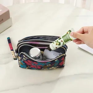 Floral print three-layer zip pouch storage bag for phone and cosmetics shown in use.