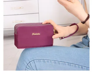 Primer plano de un bolso de mano violeta con tres cremalleras, detalle de la tela.