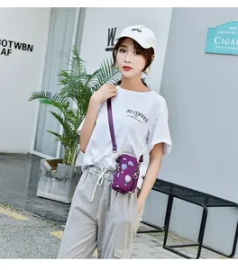 Outdoor lifestyle shot of a woman wearing a purple printed mini crossbody phone bag