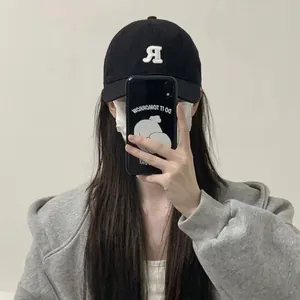 Berretto da baseball nero con ricamo 'R' bianca in un selfie allo specchio da donna