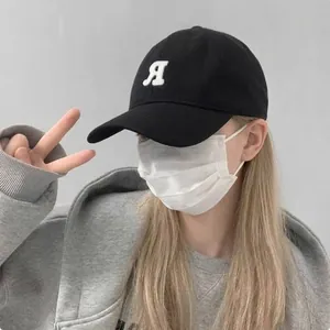 Dettaglio di un cappellino da baseball nero ricamato indossato per un effetto viso più sottile.