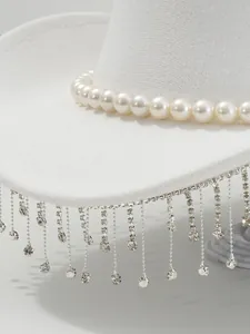 Macro detail view of elegant pearl band and sparkling rhinestone tassels on white felt hat