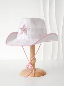 Detailansicht eines rosa Cowboyhuts mit Kuhmuster und Paillettenstern auf einem Holzständer