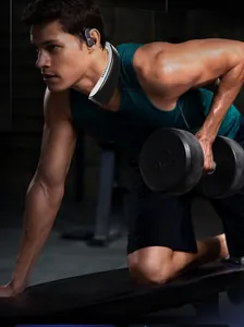 Athletic man exercising in gym wearing a portable bladeless neck fan for cooling.