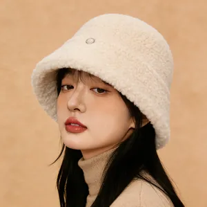 Close-up of fuzzy beige bucket hat made of warm sherpa wool worn by a model.