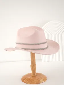 Seitenansicht eines eleganten rosa Wildlederhuts mit doppelten Strassbändern auf Holzständer