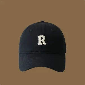 Primo piano di cappello baseball nero con lettera R ricamata bianca in rilievo