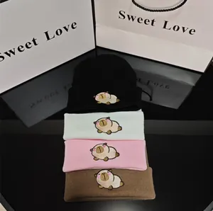 Close-up of stacked winter beanies in four colors with cute Capybara character embroidery.