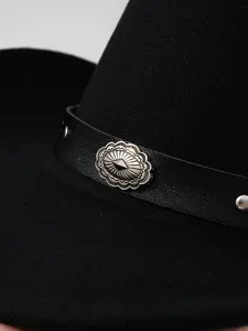 Close-up detail of silver metal ornament on black leather band of a western cowboy hat