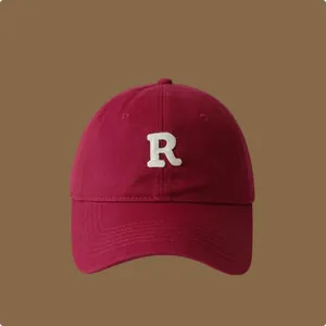 Dettaglio ravvicinato di un cappellino da baseball in cotone bordeaux con lettera R ricamata