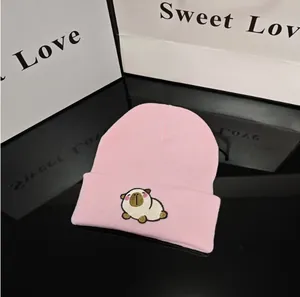 Detail view showing a cute capybara embroidery on a pink knitted winter beanie hat