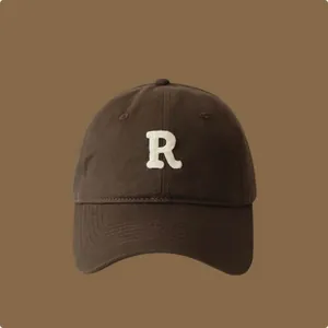Primo piano del cappellino da baseball marrone con lettera R ricamata bianca.