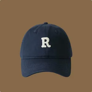 Vista dettagliata di un cappellino da baseball blu navy con lettera R ricamata.