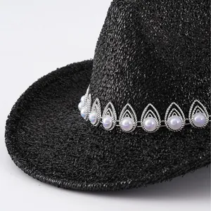 Primer plano de un sombrero vaquero negro con una banda decorativa de perlas y plata.