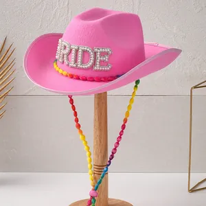 Nahaufnahme eines rosa Filz-Cowboyhuts mit RIDE-Strassbuchstaben und bunter Perlenkordel