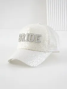 Dettaglio ravvicinato di cappello bianco con paillettes e scritta BRIDE in perle