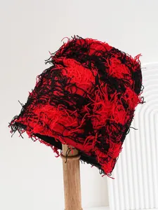 Close-up detail of red and black distressed knit balaclava showing unique fringe texture