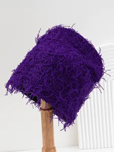 Close-up of a shaggy purple knit beanie with a fuzzy texture on a wooden stand.