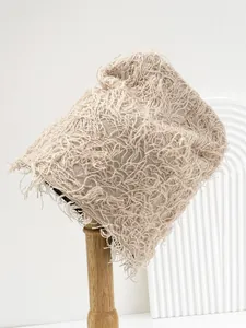 Detail view of beige distressed knitted beanie with unique fuzzy texture on stand