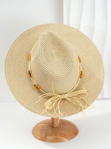Detailed view of woven straw hat featuring amber gemstones and raffia bow decoration.