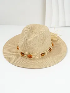 Detailed view of woven straw hat featuring amber bead trim and tassel accents.