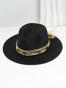 Macro view of a black woven straw sun hat featuring a decorative amber gemstone band