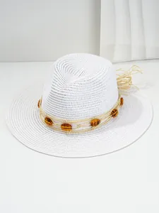 Close-up of white woven Panama straw hat featuring amber gem decorations.