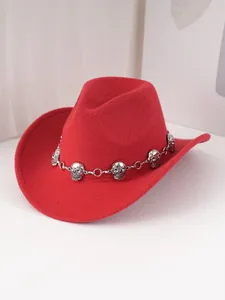 Gros plan d'un chapeau de cowboy en feutre rouge avec une chaîne à crânes argentés