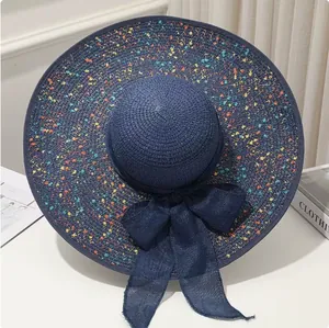 Detailansicht eines blauen Strohhutes mit bunten Spritzern und großer Schleife