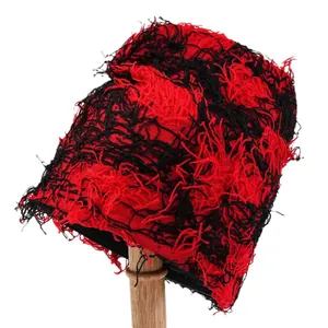 Distressed red and black knit bucket hat with shredded fringe texture on stand