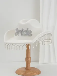 Detail of white felt cowboy hat featuring Bride rhinestone lettering and pearl fringe