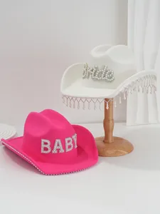 Detailed macro view of white and pink cowboy hats with pearl 'Bride' and 'BABY' lettering