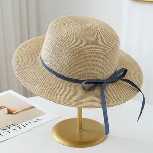 Detail view of raffia straw hat with elegant blue ribbon bow on gold stand.
