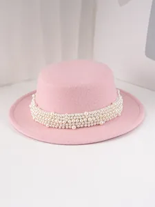 Détail d'un chapeau de feutre rose élégant avec une bande de perles décoratives